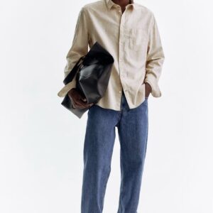 Homme portant une chemise claire et un jean dans un univers de mode durable